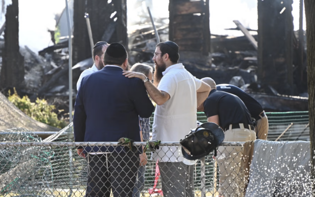 Le rabbin Yitzchok Lerman, qui a survécu avec sa famille à l'incendie qui a complètement détruit la synagogue Beth El, se tient devant les ruines de la synagogue à Rutherford, dans le New Jersey, le 8 août. (Crédit : Kyle Mazza/Anadolu via Getty Images via JTA)